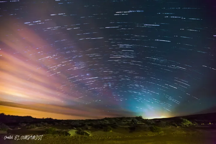 Ciel en mouvement, Traînées d'étoiles en arcs au-dessus d'une lande, ciel rose et bleu