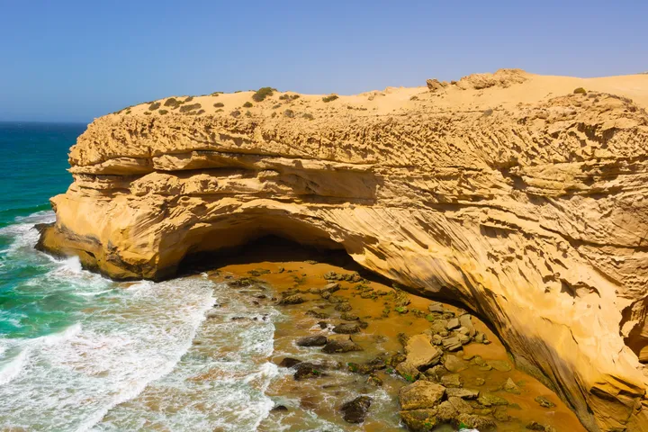 L'arche de sable, Falaise de sable en forme d'arche au-dessus de vagues turquoise