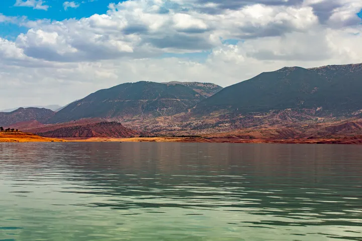 Montagnes rouges, Montagnes rouges au bord d'un lac vert sous un ciel nuageux
