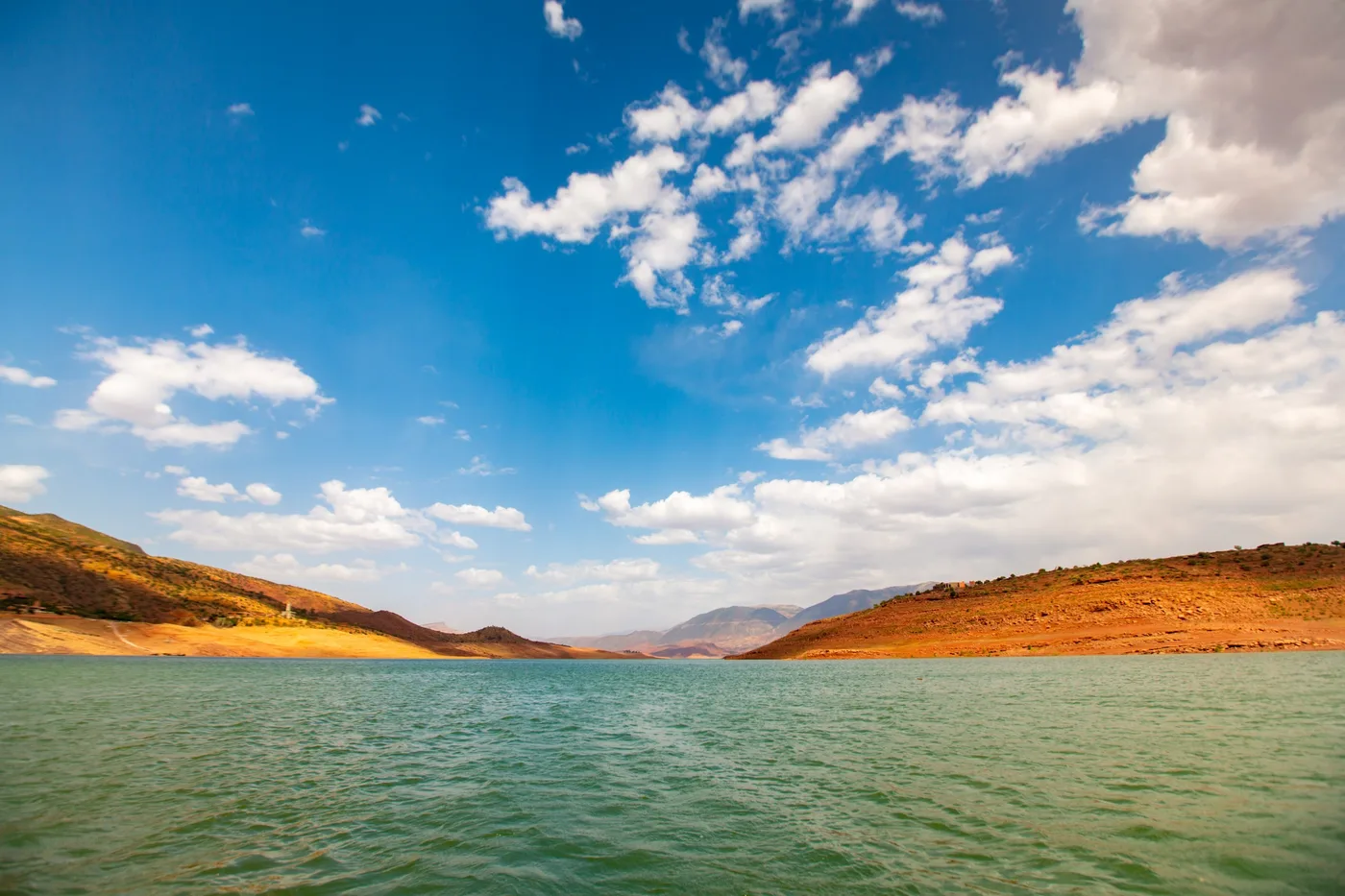 Ciel de lac, Grand ciel nuageux au-dessus d'un lac entre des collines rouges