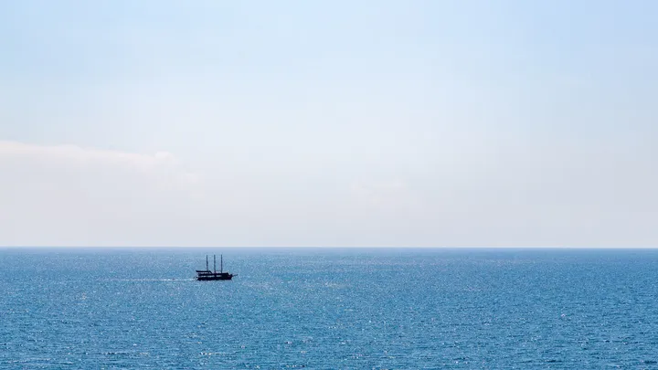 Le voilier, Petit voilier trois-mâts sur une mer calme sous un ciel pâle