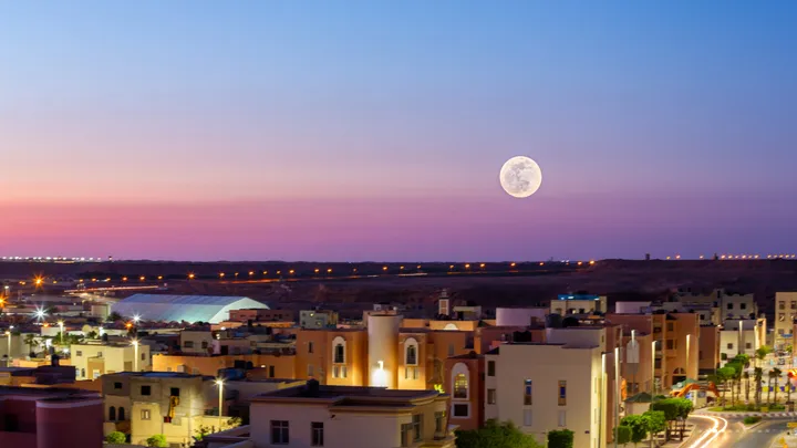 Lune sur la ville, Pleine lune dans un ciel rose et mauve au-dessus d'une ville