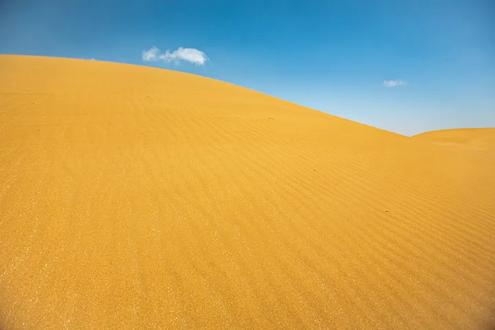 La dune, Courbe de dune de sable doré contre un ciel bleu