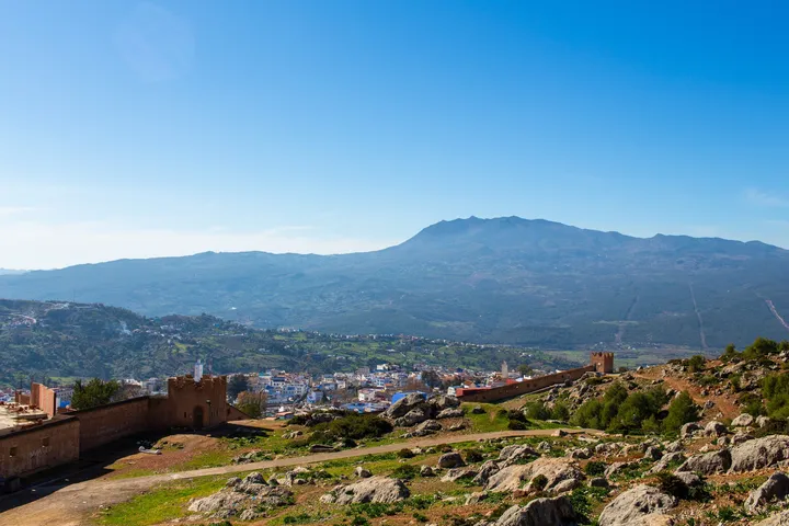 La kasbah et la montagne, Remparts de kasbah, ville et montagne sous un ciel bleu