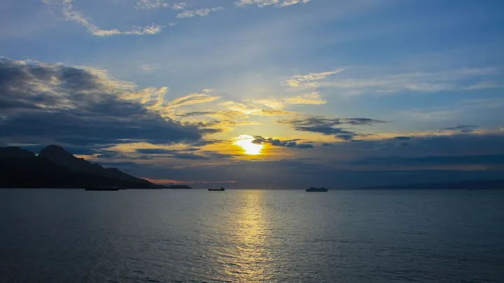 Soir sur la mer, Coucher de soleil sur une mer calme avec des cargos au loin
