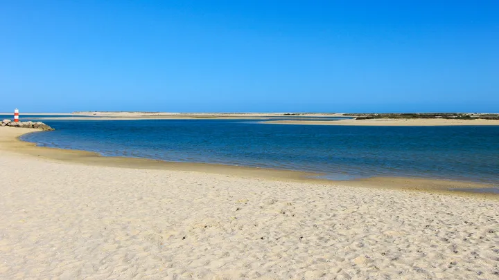 Lagune I, Lagune calme bordée de sable clair avec un phare au loin