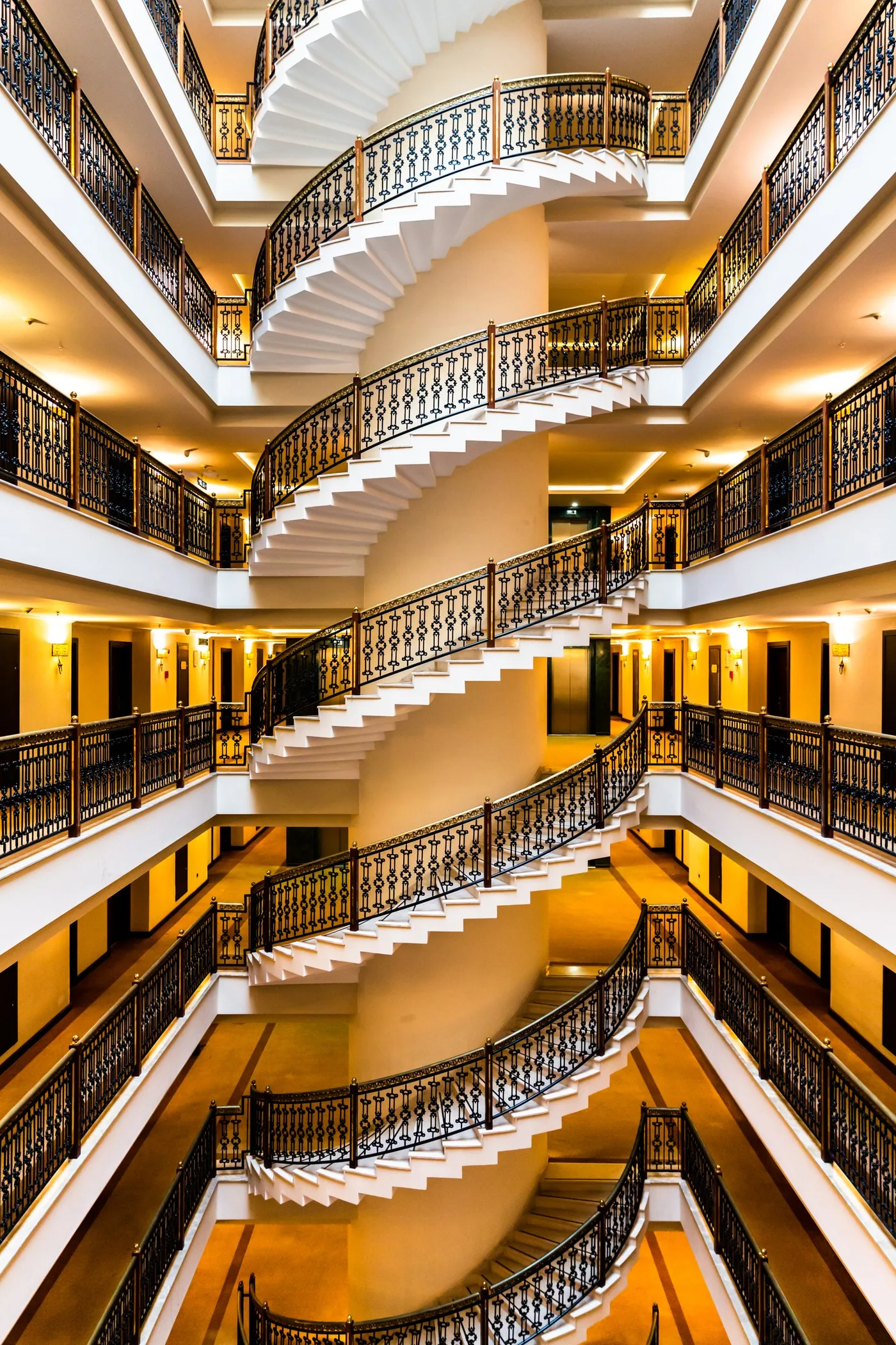 Escalier infini, Escalier en colimaçon vu d'en haut, rampes en fer forgé et lumière dorée