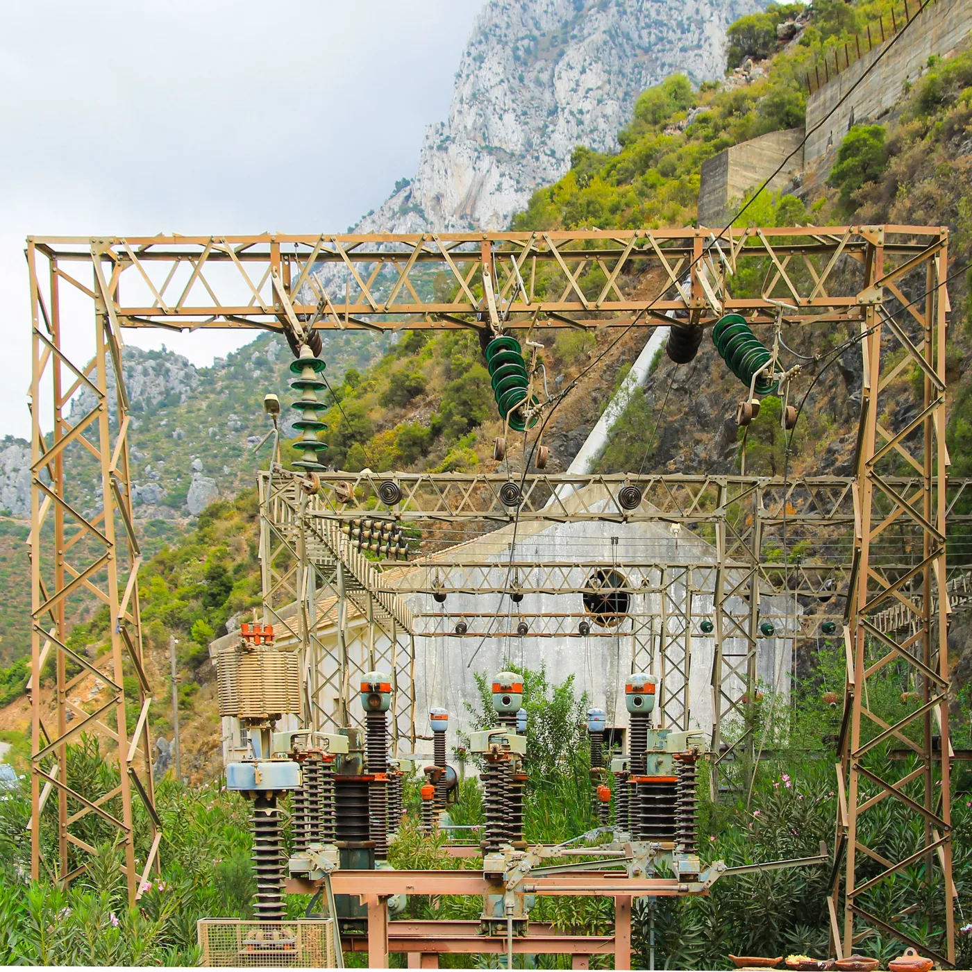 Haute tension, Poste électrique et structures métalliques au pied d'une falaise