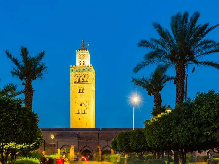 Koutoubia, heure bleue, Minaret de la Koutoubia illuminé sur un ciel bleu profond, palmiers