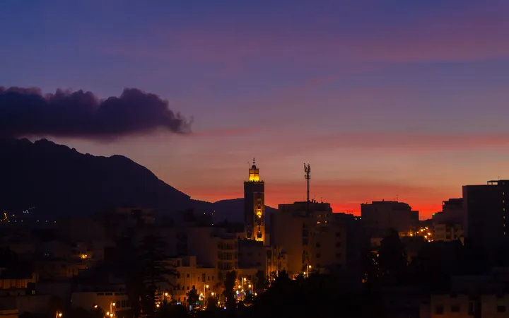 Minaret au couchant, Minaret éclairé sur un ciel rouge et mauve au pied des montagnes