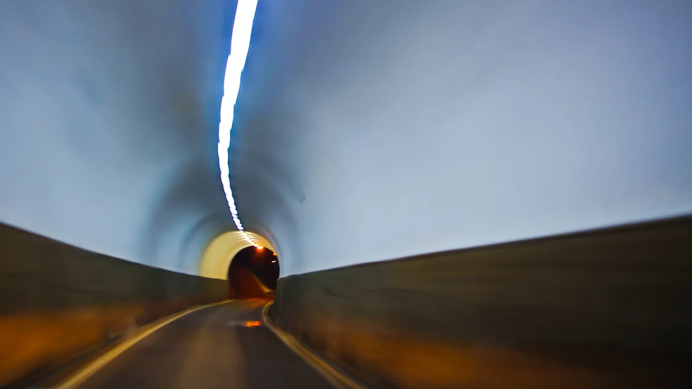 Le tunnel, Tunnel de nuit avec une traînée lumineuse au plafond et une sortie éclairée au fond